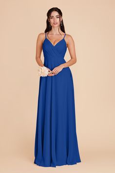 a woman wearing a blue bridesmaid dress and holding a flower in her hand