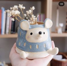 a hand holding a ceramic bear planter