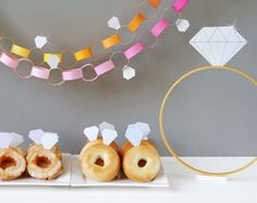 three donuts sitting on top of white trays next to a string of bunting