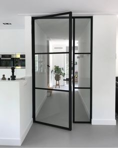 an open glass door leading to a kitchen and living room with black accents on the walls