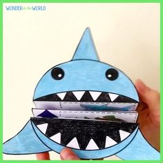 someone is holding up a card holder made to look like a shark with its mouth open