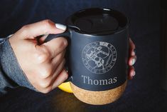 a person holding a coffee cup with the word thomas on it