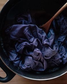 a wooden spoon in a pot filled with purple cloth