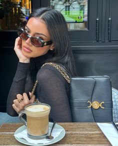 a woman sitting at a table with a cup of coffee