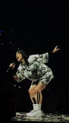 a woman in white and black outfit on stage with her arms out to the side