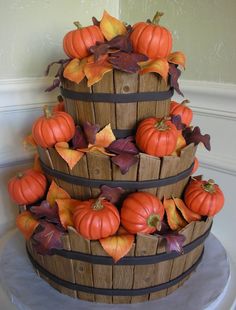 a three tiered cake decorated with pumpkins and leaves