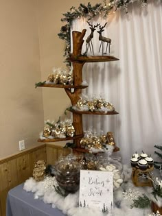 a table topped with cakes and cupcakes covered in frosted snow next to a christmas tree