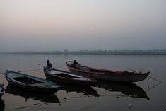 three small boats sitting on top of a lake next to each other in the evening