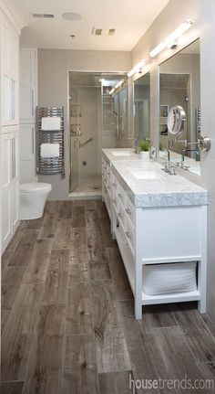 a bathroom with wood floors and white cabinets