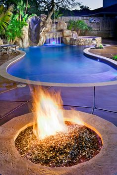 an outdoor fire pit with a pool in the background