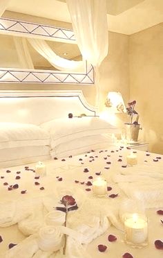 a bed with rose petals and candles on it