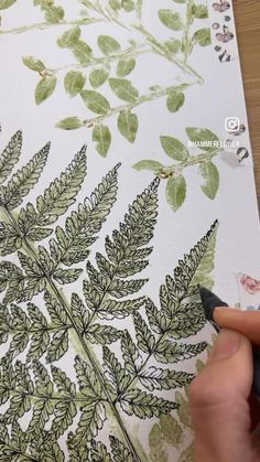 someone is drawing leaves on a piece of paper