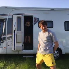 a man standing in front of an rv with the door open and his feet propped up