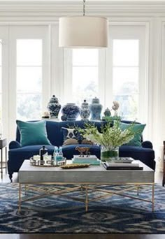 a living room with blue couches and vases on the table in front of them