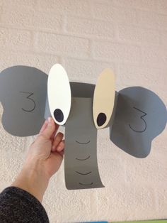 someone is holding up an elephant cut out of paper to make it look like they are smiling