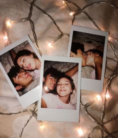 three polaroids are laying on a bed with christmas lights around them and there is no image to describe