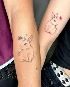 two people with tattoos on their arms holding each other's hands and one has a rabbit tattoo on it