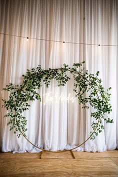 a wedding arch with greenery and the word welcome is displayed in front of a curtained backdrop