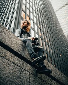 a man sitting on the side of a tall building looking up at something in front of him