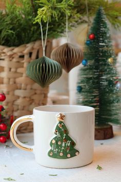 a coffee cup with a christmas tree on it and ornaments hanging from the ceiling behind it