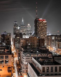 the city skyline is lit up at night, with tall buildings in the foreground