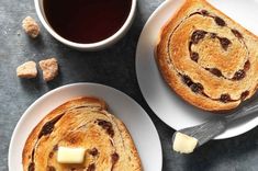 two white plates with slices of bread and butter on them next to a cup of coffee