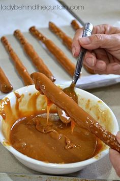 a person dipping some kind of sauce in a bowl with pretzels on the side