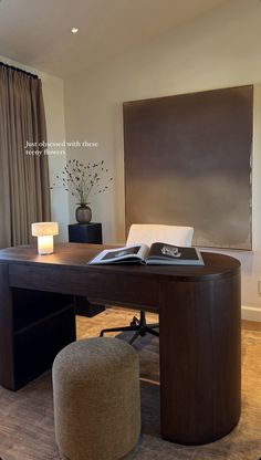 an open book on top of a wooden desk in front of a window with curtains