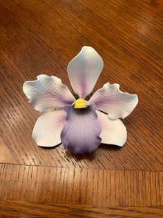 a purple flower sitting on top of a wooden table