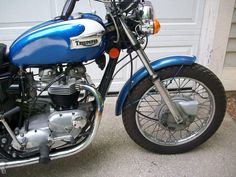 a blue and white motorcycle parked in front of a garage