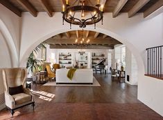 an open living room and dining area with wood flooring, chandelier and white walls