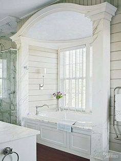 a bathroom with a tub, sink and shower in it's corner area next to a window