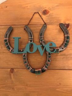 a horseshoe shaped sign with the word love hanging from it's side on a wooden wall