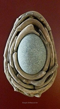 a circular mirror made out of driftwood on a red wall above a toilet paper dispenser