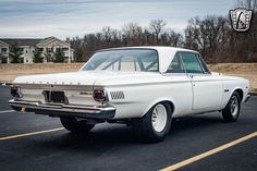 an old white car parked in a parking lot