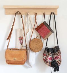 three purses hanging on a wall with two bags