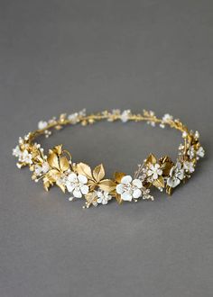 a gold headband with white flowers and leaves on the side, sitting on a gray surface