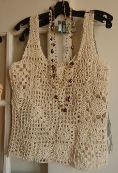 a crocheted top hanging on a door with beads and chains attached to it