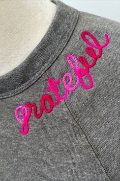 a gray shirt with pink lettering on it