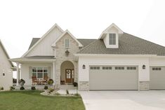 a white house with two garage doors and windows