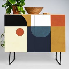 a plant is sitting on top of a cabinet with geometric designs and shapes painted on it