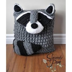 a crocheted raccoon bag sitting on top of a wooden floor