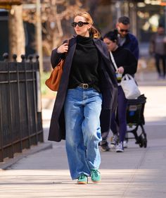 a woman walking down the street with her hand in her pocket