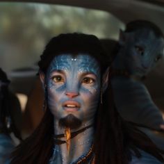 a man with blue paint on his face and long dreadlocks sitting in a car