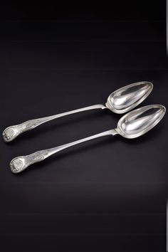 three silver spoons sitting next to each other on a black surface