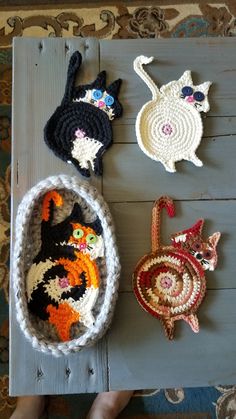 four crocheted cats sitting on top of a wooden table