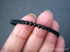 a hand holding a black beaded string with beads in it's middle and the end