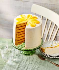 there is a cake with yellow flowers on it and two plates next to the cake