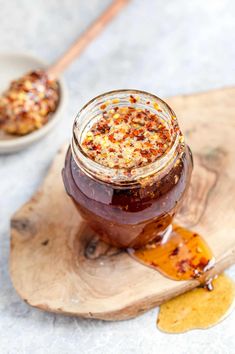 a jar filled with jam sitting on top of a wooden cutting board next to a spoon