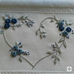 embroidered heart with blue flowers and leaves on white linen background, ready to be sewn